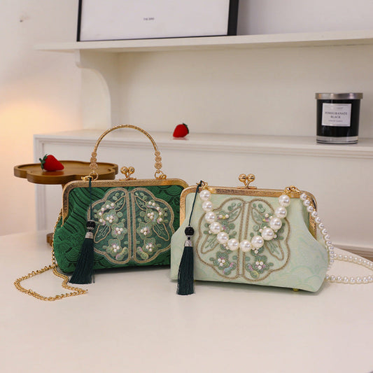 Two embroidered handbags with tassels on a white surface.