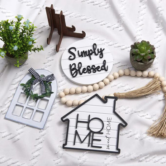 Decorative items including a house-shaped sign, wreath, and 'Simply Blessed' plaque on a textured white surface.