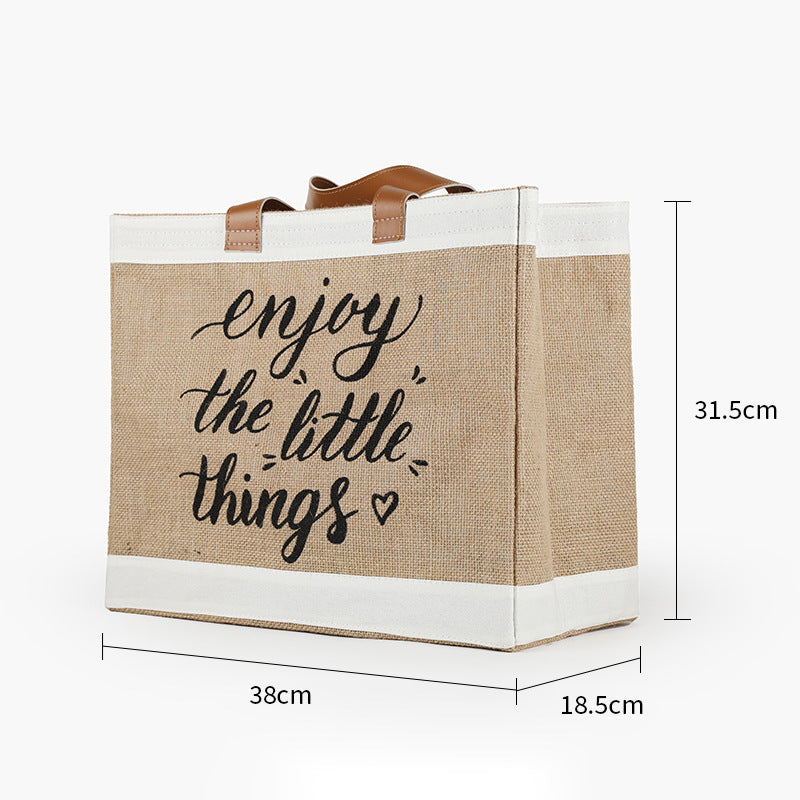 Jute bag with 'enjoy the little things' text and dimensions on a white background