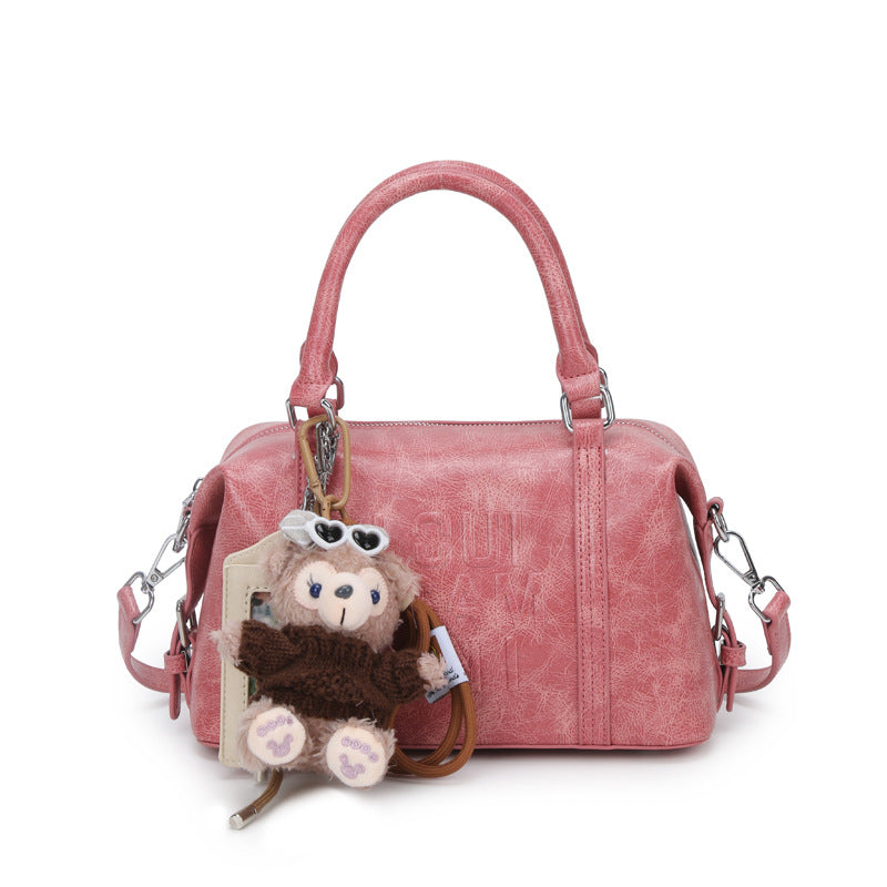 Pink handbag with a monkey keychain on a white background