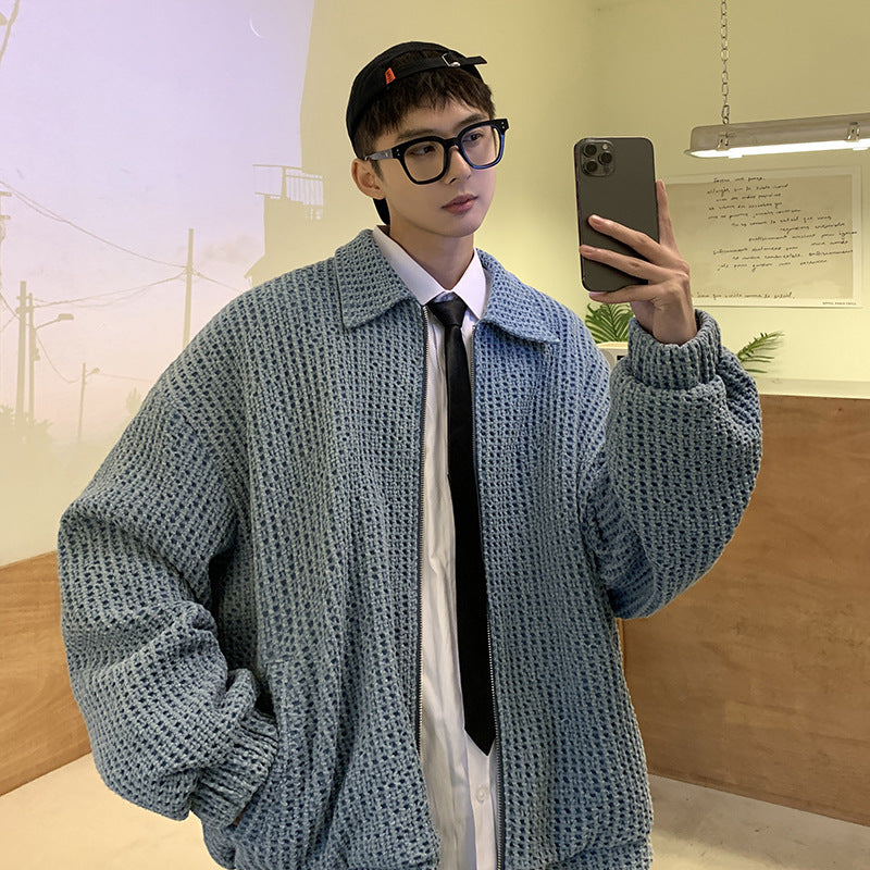 Person wearing a textured blue sweater taking a mirror selfie indoors.
