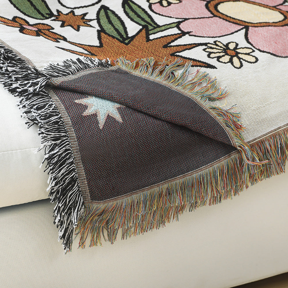 Decorative throw blanket with fringe on a floral-patterned surface