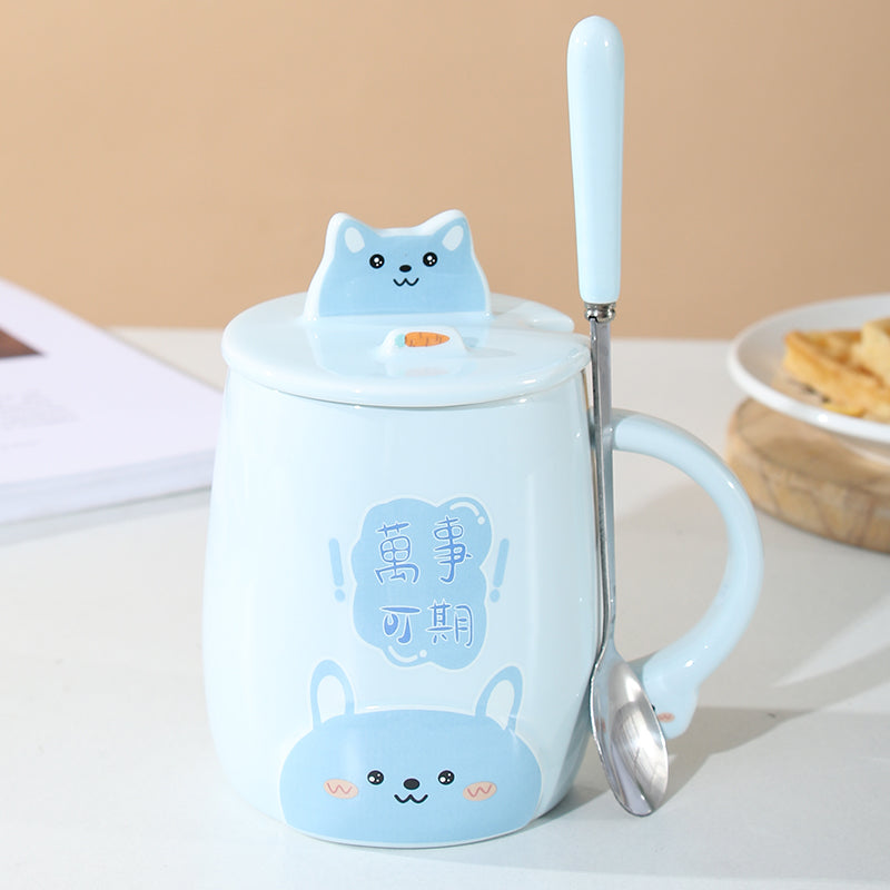 Blue mug with a cat design, lid, and spoon on a beige background