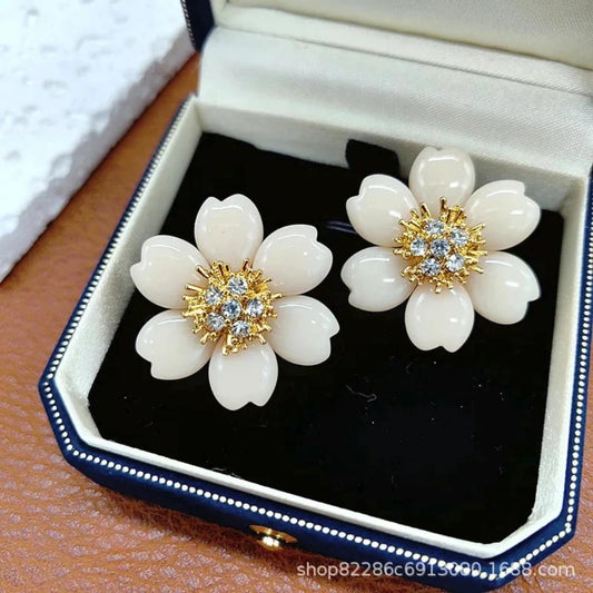 Flower-shaped earrings with gold and crystal centers in a jewelry box.
