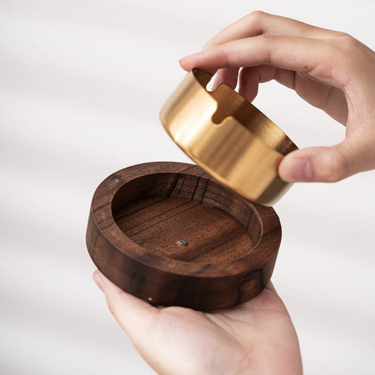 Wooden container with a gold lid held by a hand on a white background