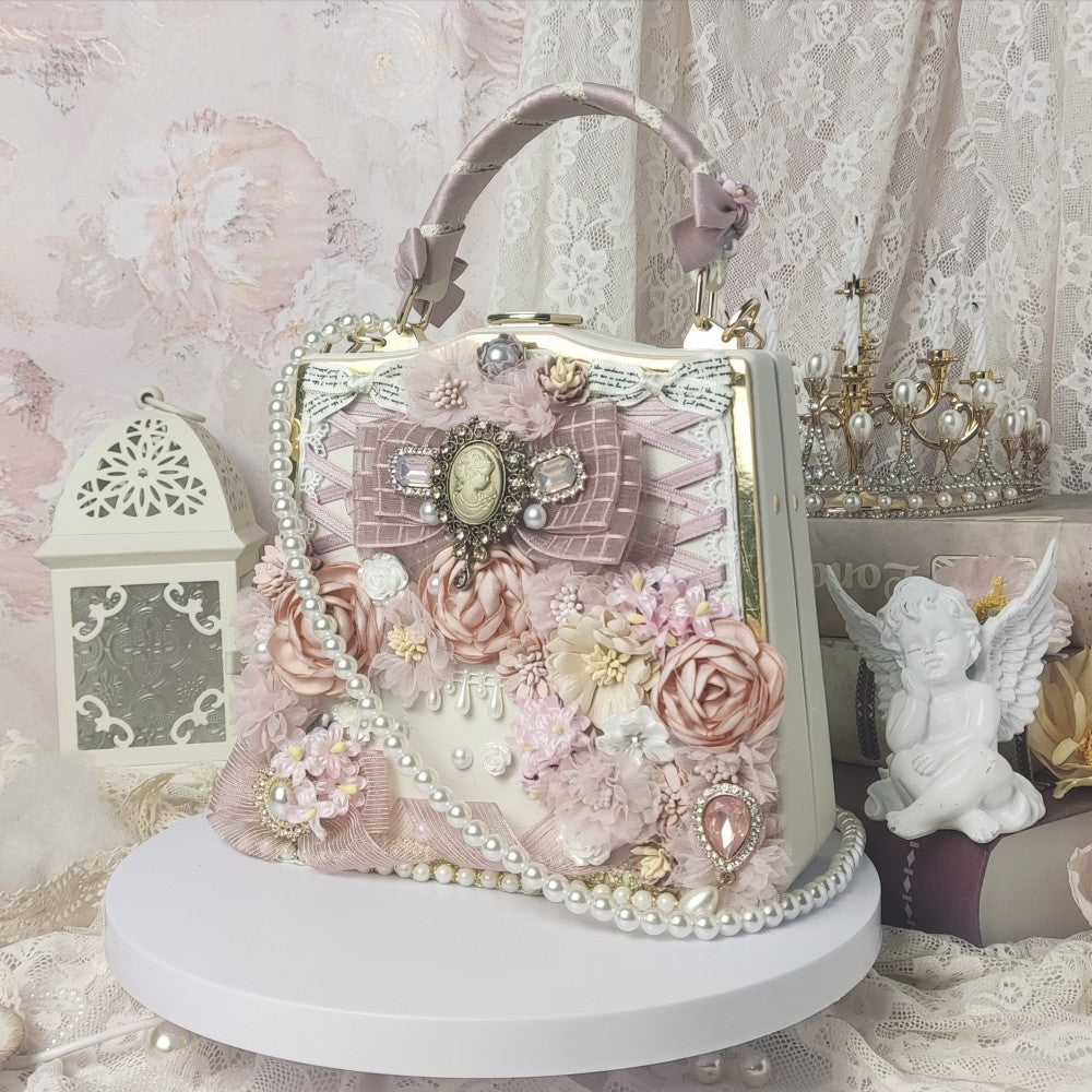 Decorative handbag with floral and pearl details on a white platform against a lace curtain background.
