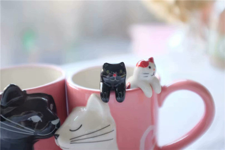 Pink mug with cat-shaped ceramic tea infusers on a blurred background