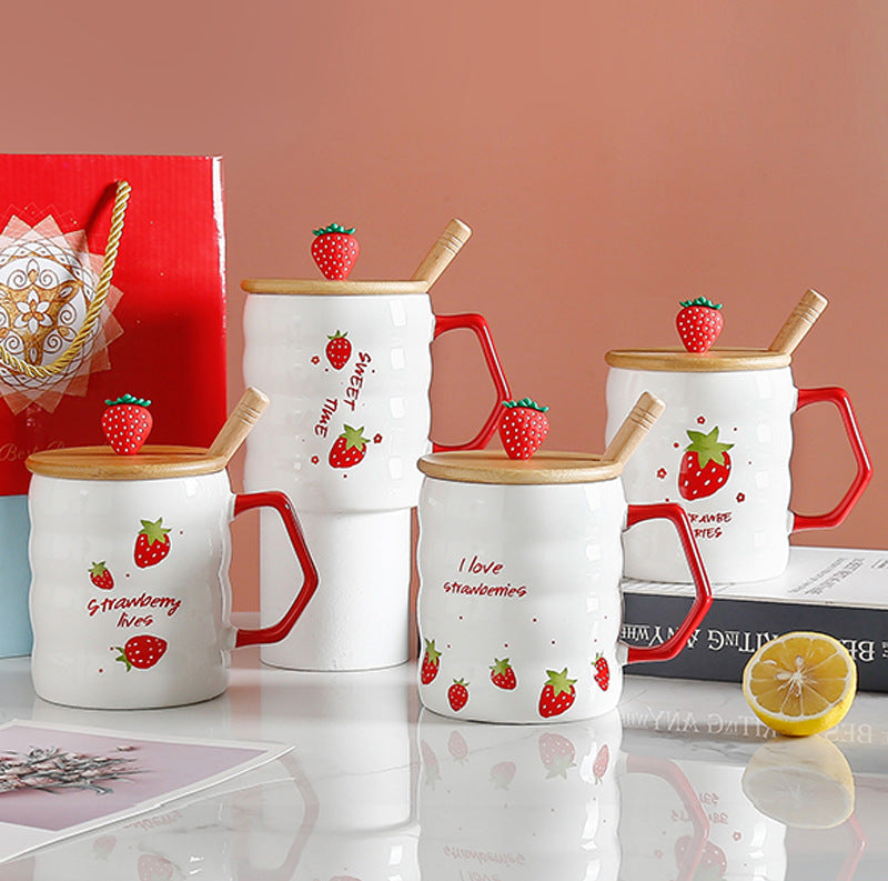 Set of white mugs with strawberry designs and red handles on a reflective surface.
