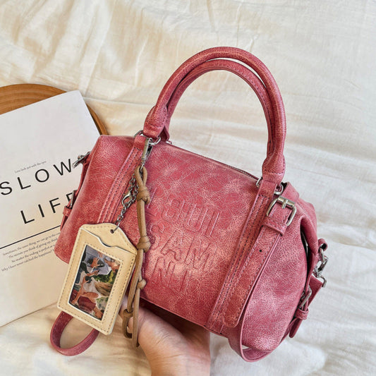 Pink handbag with 'Slow Life' tag held by a hand on a light background