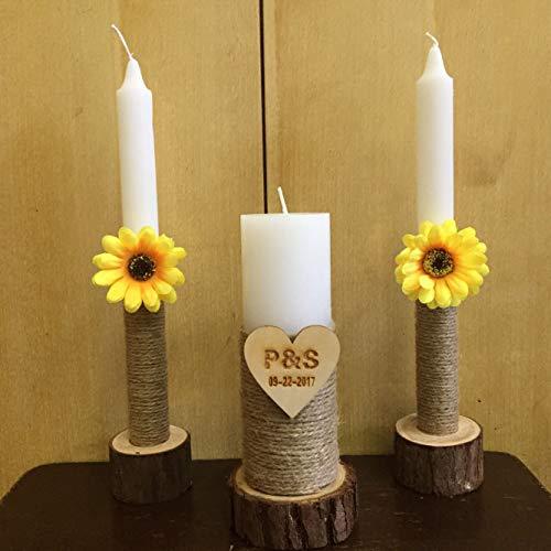 Three candles with sunflower decorations and a heart-shaped plaque on a wooden surface.