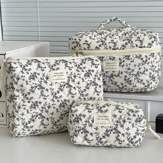Set of floral-patterned travel bags on a light surface with a neutral background