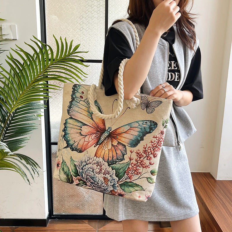 Person holding a tote bag with butterfly design indoors