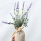 Artificial lavender plant in a burlap bag against a light background