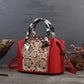 Red handbag with intricate design and patterned handle on a dark background