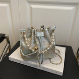 Decorative bucket bag with pearl embellishments on a book titled 'Greatest River'.