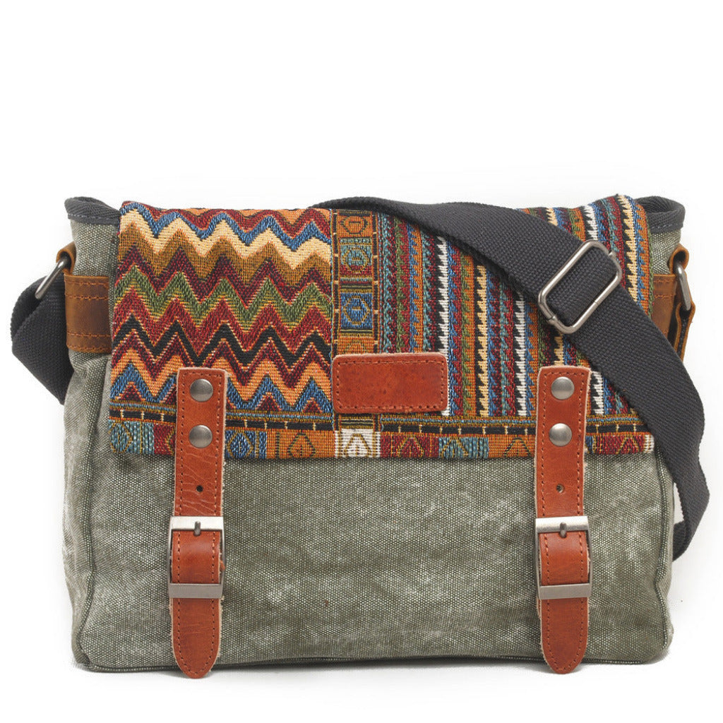 Multicolored patterned bag with gray strap and brown leather accents on a white background