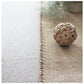 Woven decorative ball on a textured surface with a blurred background