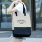 Person holding a beige tote bag with text outdoors