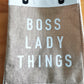 Tote bag with 'BOSS LADY THINGS' text on a wooden surface