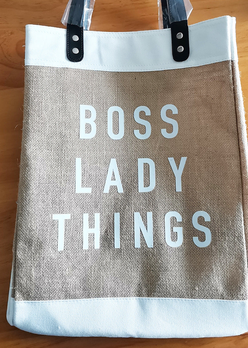 Tote bag with 'BOSS LADY THINGS' text on a wooden surface