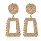 Gold earrings with spherical top and rectangular frame on a white background
