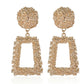 Gold earrings with spherical top and rectangular frame on a white background