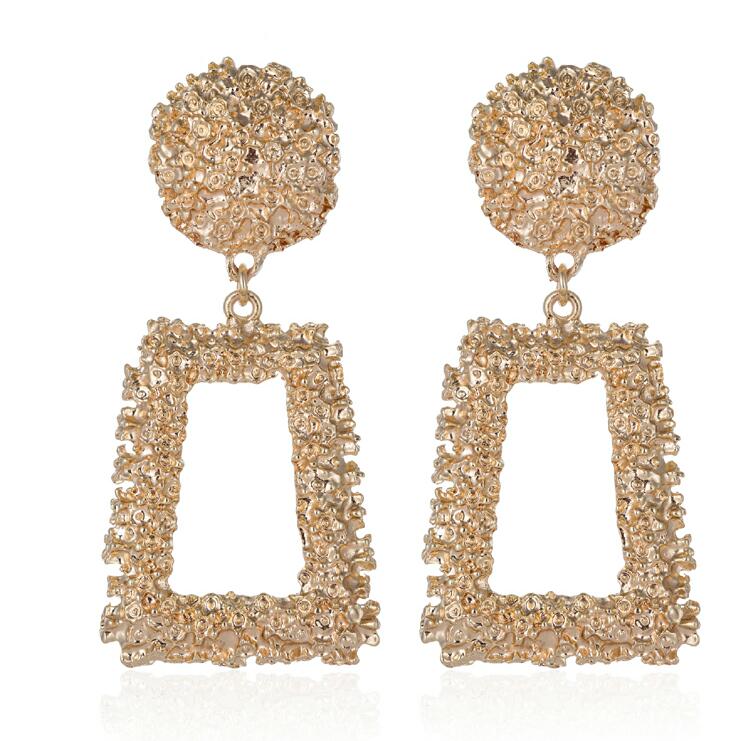 Gold earrings with spherical top and rectangular frame on a white background