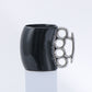 Black mug with a silver knuckle-duster handle on a white background