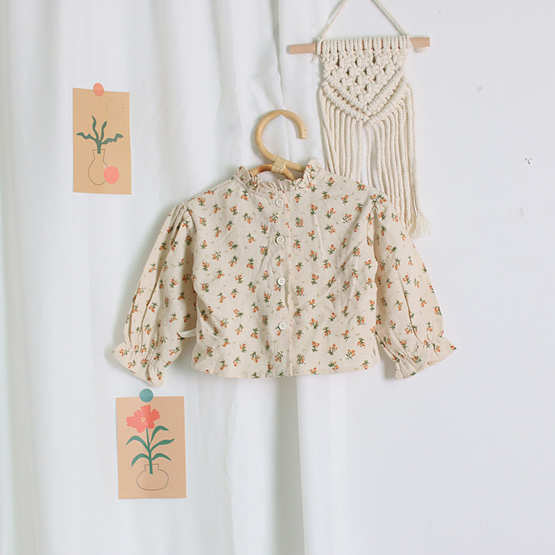 Floral blouse on a hanger with macrame wall art and cards with plant illustrations on a white background