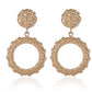 Gold hoop earrings with intricate designs on a white background