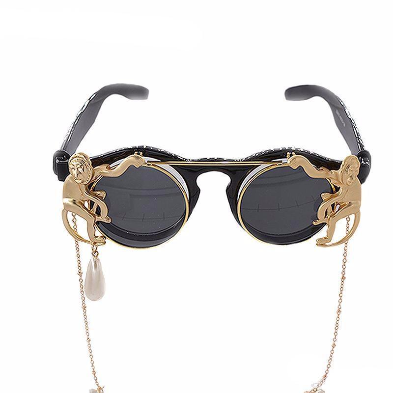 Sunglasses with gold monkey designs and chains on a white background