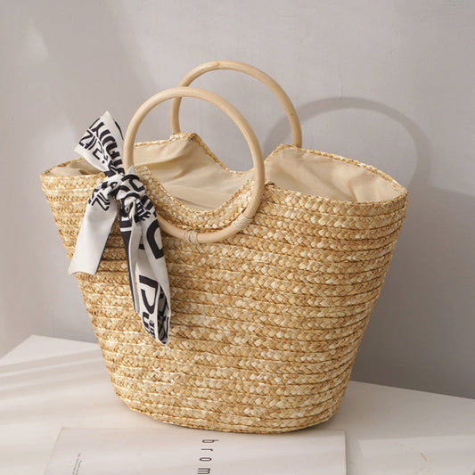 Woven straw bag with a decorative ribbon on a light surface.