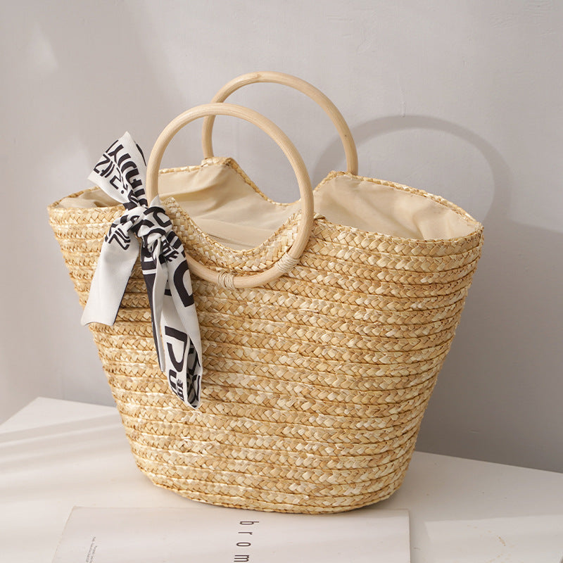 Woven straw bag with a decorative ribbon on a light surface.