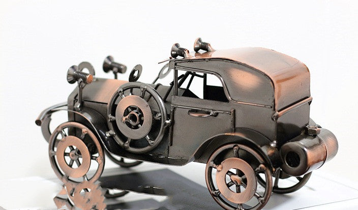 Metallic model of an old-fashioned car on a reflective surface with a white background