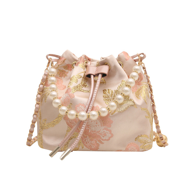 Decorative bag with floral patterns and pearl accents on a white background