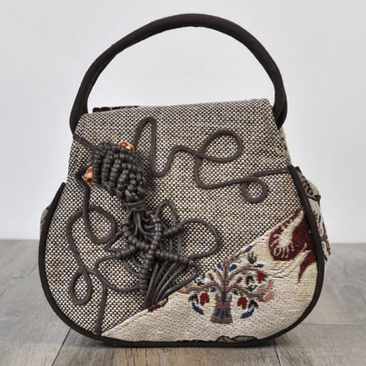Handbag with floral embroidery and decorative elements on a light background
