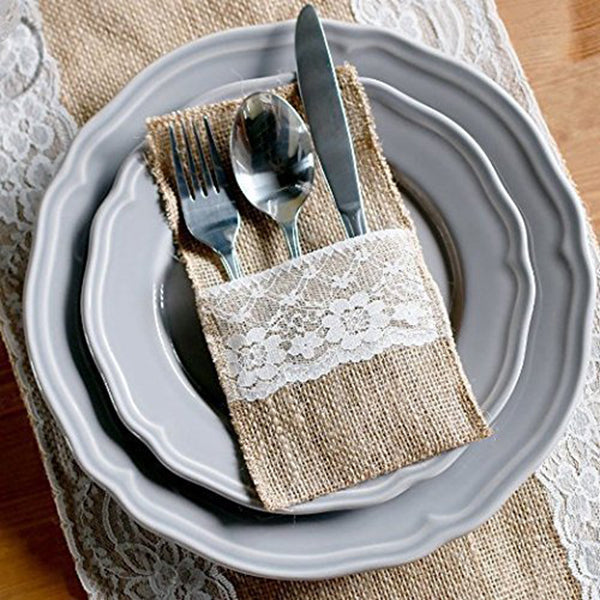 Silverware set on a decorative napkin with lace trim on a gray plate.