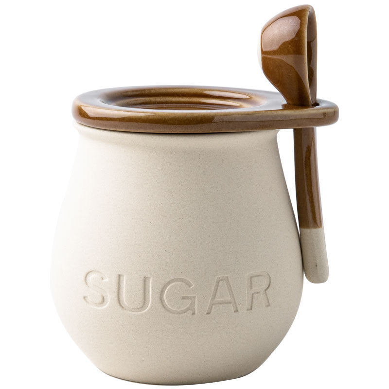 Ceramic sugar container with a brown lid and spoon on a white background