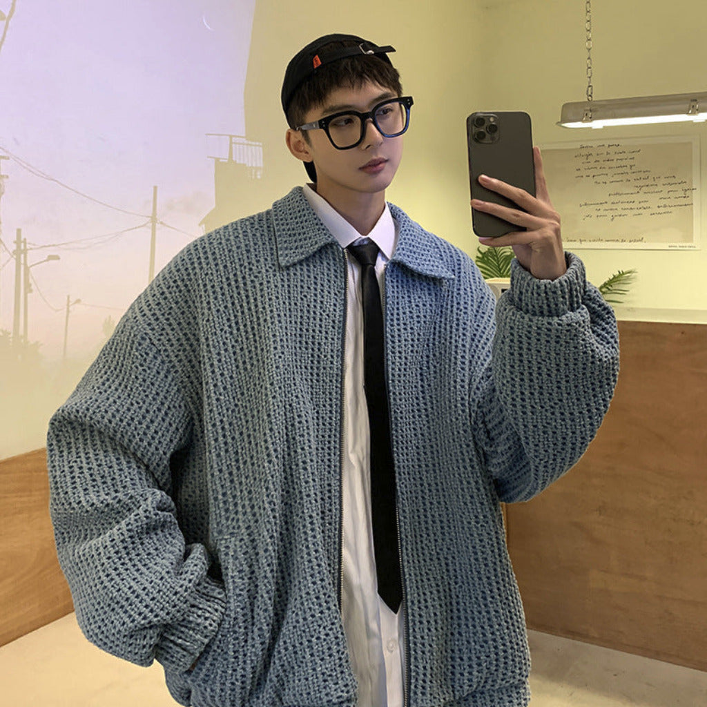 Person wearing a textured blue sweater taking a mirror selfie indoors.