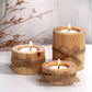 Three wooden candle holders with candles, tied with jute twine, on a light background.