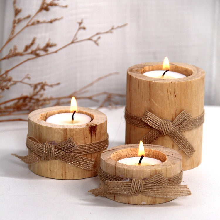 Three wooden candle holders with candles, tied with jute twine, on a light background.
