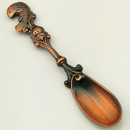 Decorative spoon with ornate handle on a light gray background