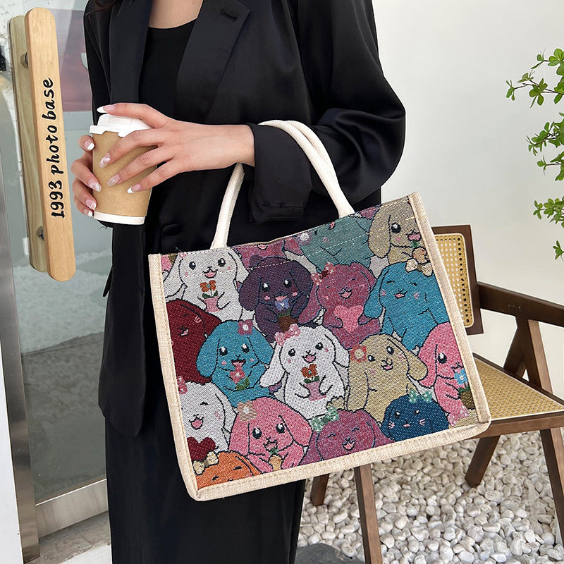 Person holding a tote bag with dog illustrations and a coffee cup, standing outdoors.