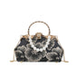 Black floral handbag with pearl embellishments on a white background