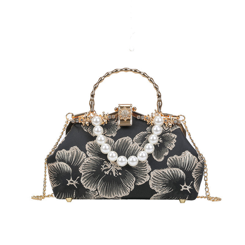 Black floral handbag with pearl embellishments on a white background