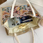 Tote bag with butterfly pattern interior, containing a phone, notebook, and other items.