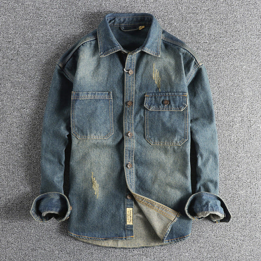 Denim shirt with rolled-up sleeves on a gray textured background