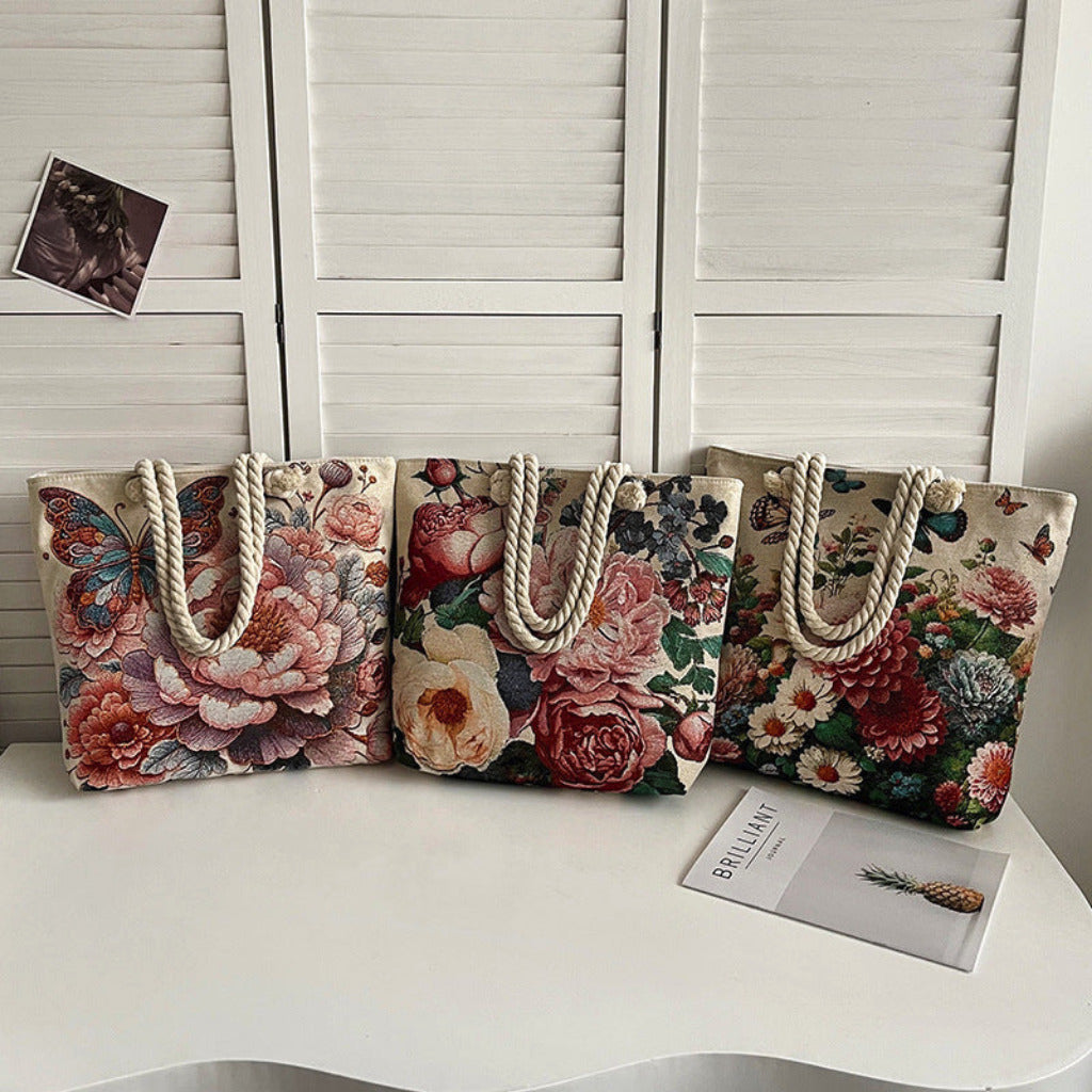Four floral tote bags with rope handles on a white surface.