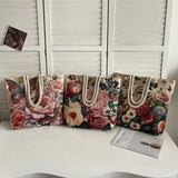 Four floral tote bags with rope handles on a white surface.