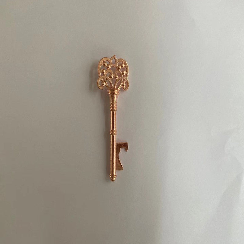 Decorative gold key-shaped bottle opener on a light gray background